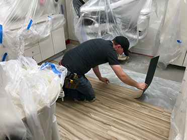 Flooring Technician installing vinyl flooring during turnkey dental office renovation